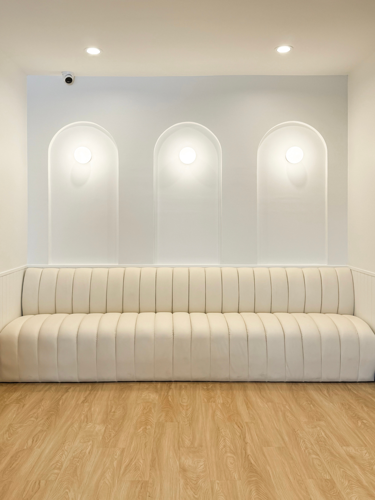 Curved cream sofa beneath illuminated wall arches